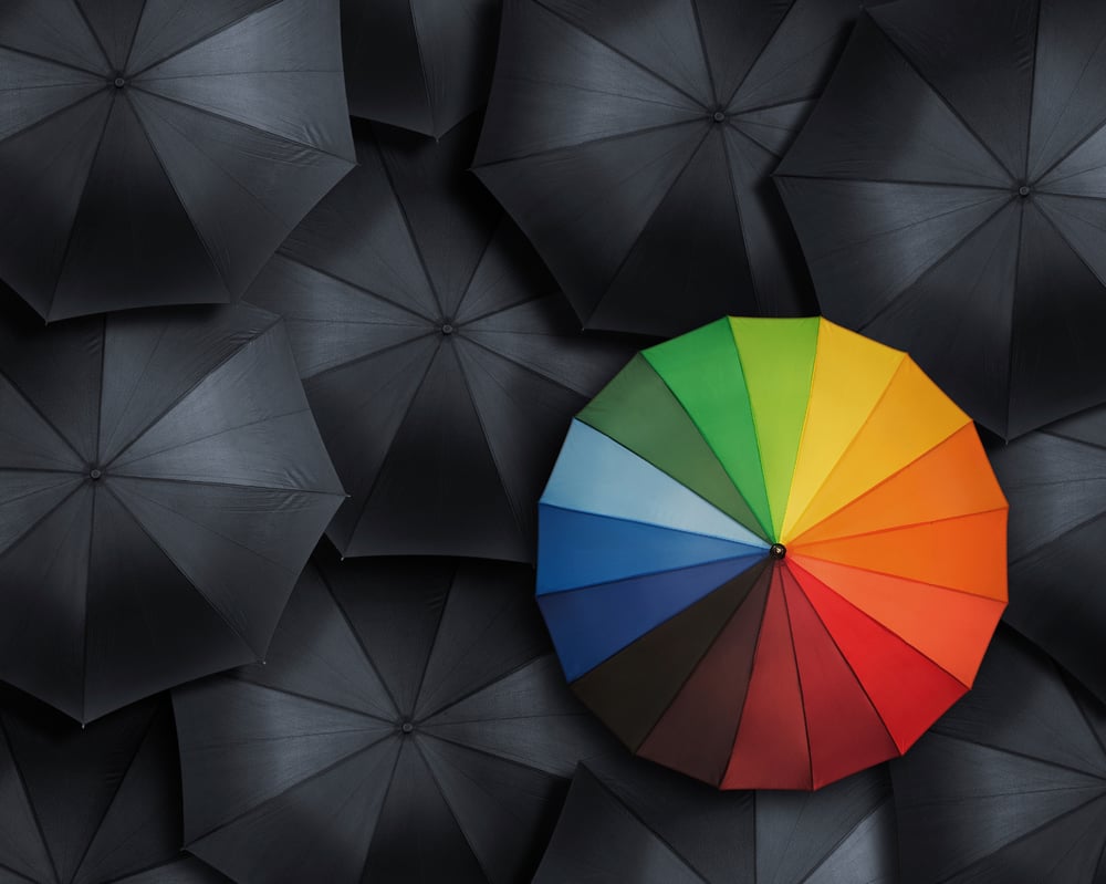 One multi-coloured umbrella in a sea of black umbrellas