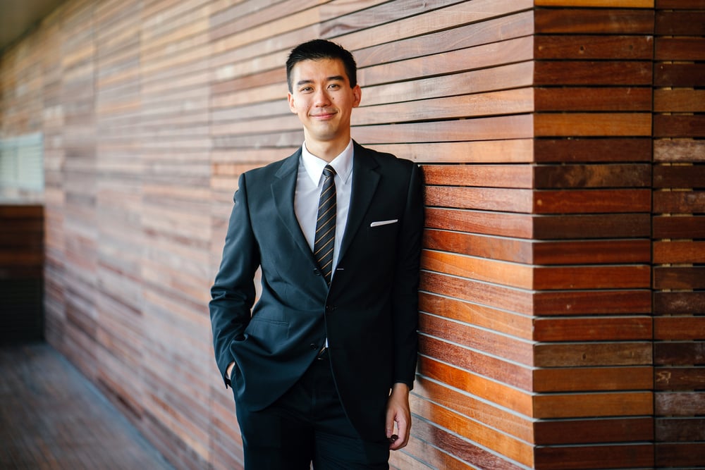 Young business man leaning against a timber slat wall