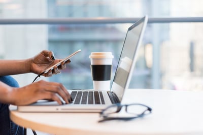 Woman's hands with laptop, phone and coffee