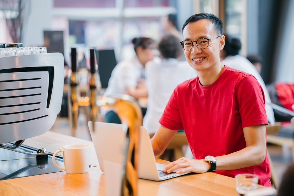 Young man in t-shirt working on laptop in cafe