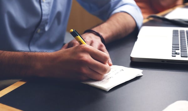 Man writing notes with a pen and paper