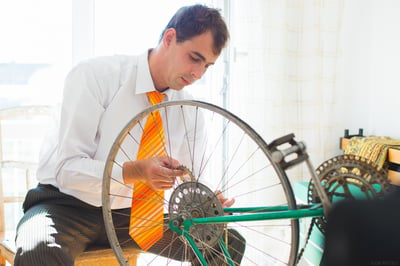 Man in business attire repairing a bike