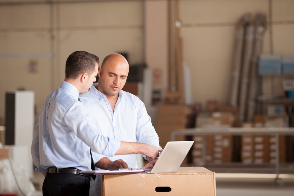 Two businessmen with laptop in factory