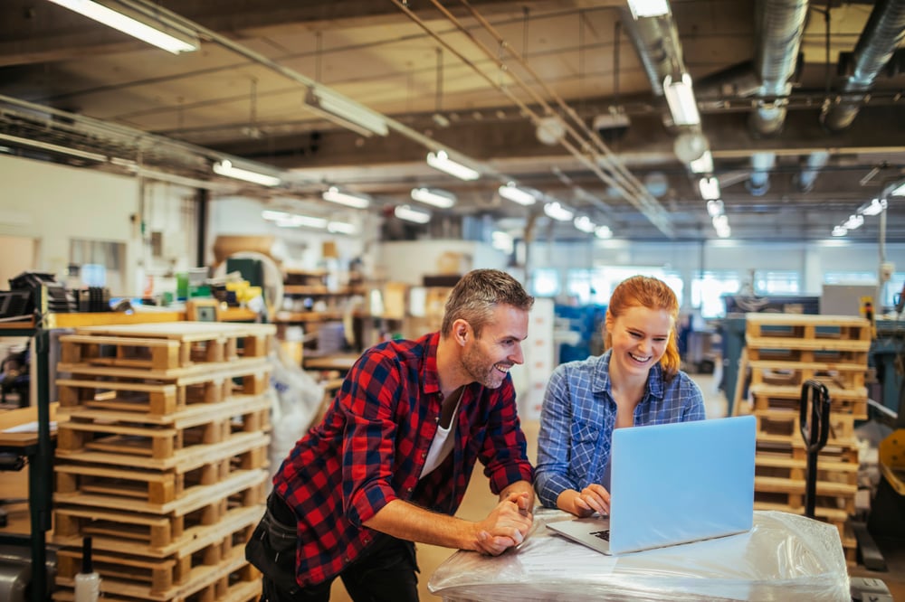 Two people working on laptop in factory