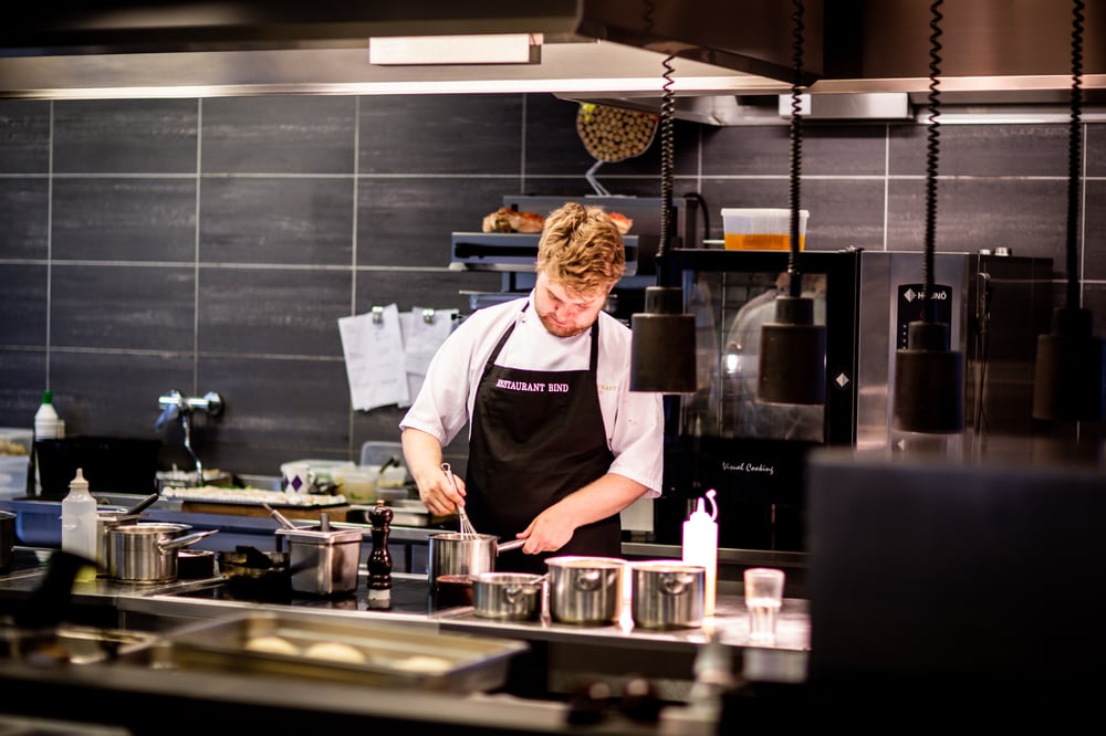 Man in chef's apron working in bar kitchen