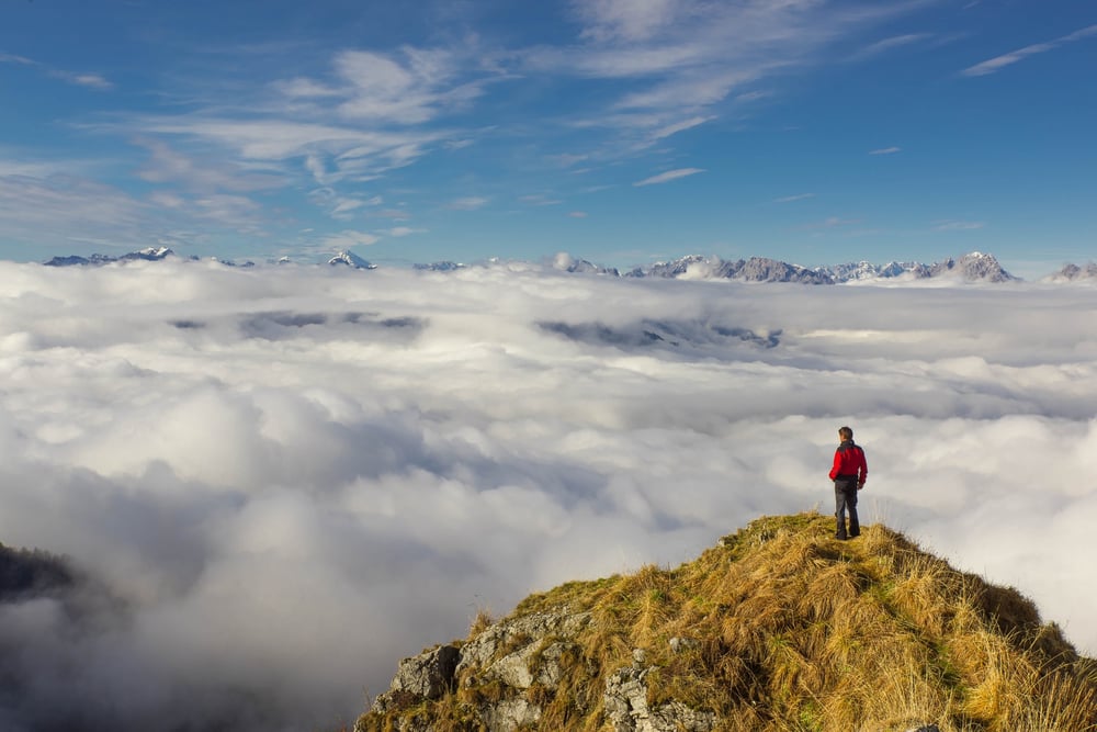 Hiker on a mountain looking down at clouds
