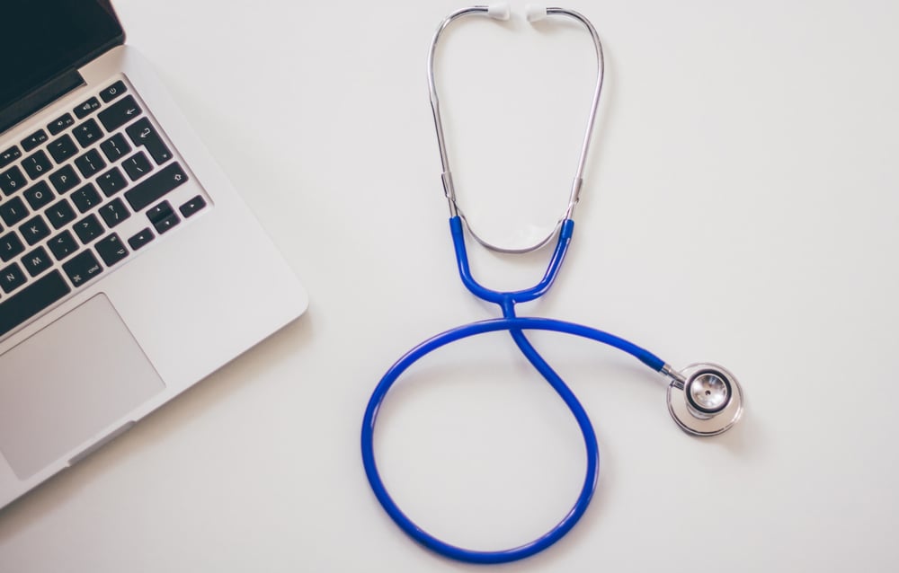 laptop and blue stethoscope on desk