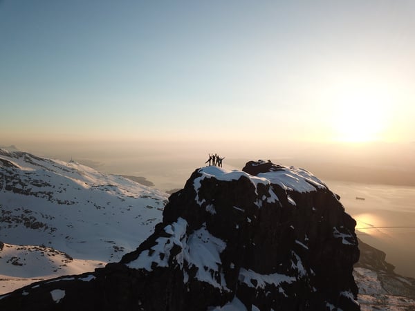 four-people-above-snow-covered-mountain-top-2403502