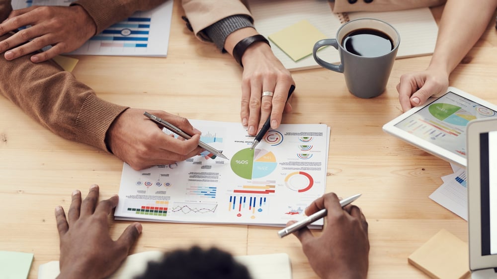 People's hands visible as they discuss graphs on a table