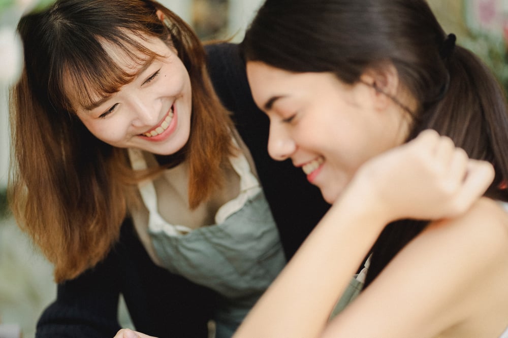 Woman wearing work apron smiling at younger woman