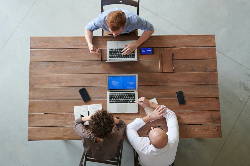 Three people at business meeting photographed from above