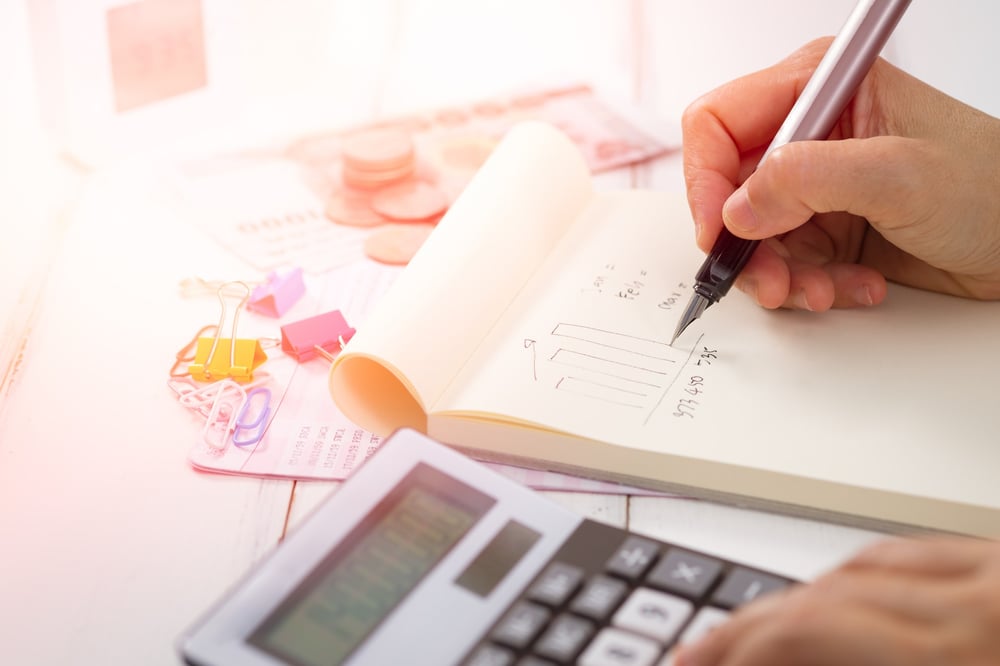 Person's hand doing a calculation on a notepad