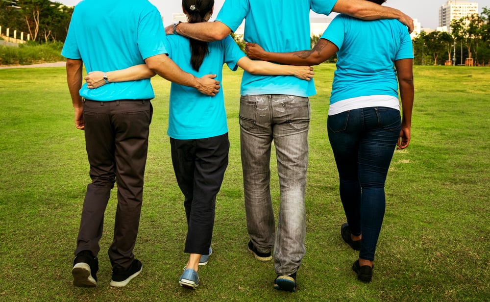 Pictured from behind, two men and two women walking with arms around each other