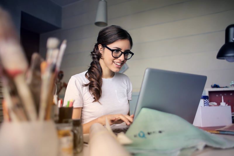 Woman smiling and working on a laptop computer