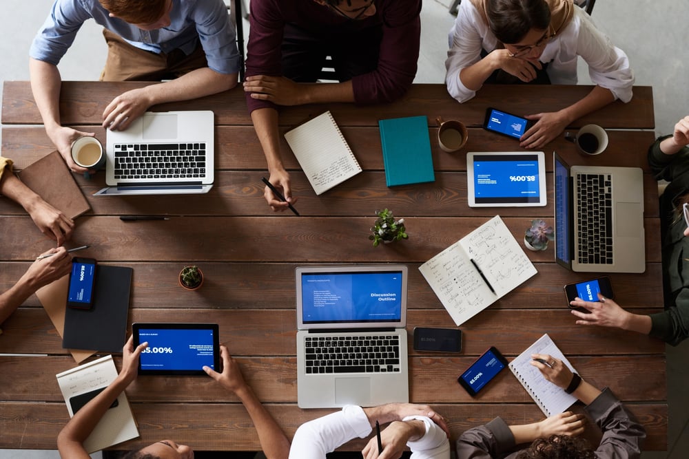 top view of 8 people sitting around a table at a business meeting