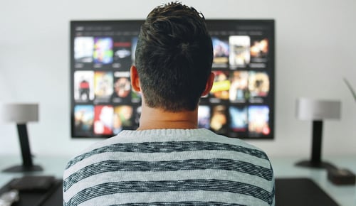 Photo taken from behind of man watching TV