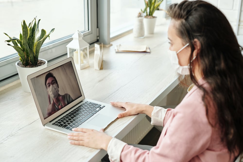 Woman and man having a video call while wearing face masks